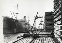 168946 Afbeelding van het lossen van nog onbehandelde dwarsliggers in de haven bij het houtbereidingsbedrijf (HBI) van ...